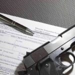 Handgun on firearm transaction form with pen