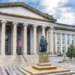 Neoclassical government building with columns and a central bronze statue