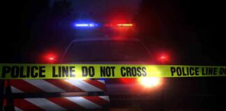 Police car behind crime scene tape at night