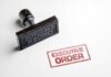 Rubber stamp leaving a red executive order imprint on white paper