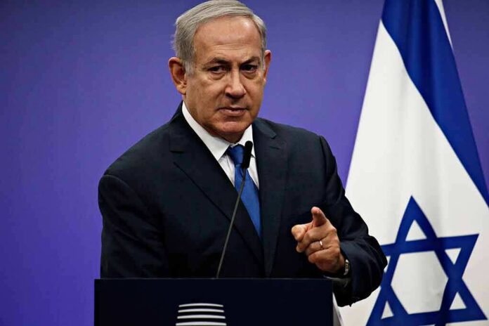 shutterstock_1042782061 man in suit speaking at a podium with an Israeli flag
