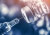 syringe needle drawing liquid from a vaccine vial