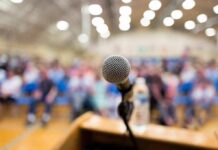 On-Tape Meltdown: Mayor Charges A Critic microphone on a podium facing a blurred audience