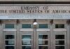 United States embassy entrance with metal doors and security camera