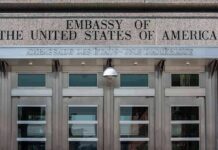 United States embassy entrance with metal doors and security camera