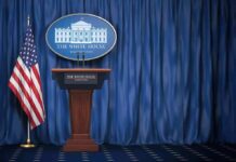 Record-Breaking Ouster Rattles Press Room White House press briefing podium with U.S. flag and blue curtain