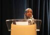 Trump Targets Omar Over Alias Twist Woman in hijab speaking at a podium