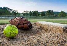 Softball and glove near a base on a dirt field