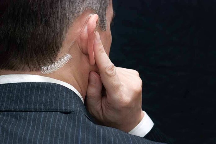 Man in suit with earpiece touching his ear