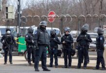Iran Fingerprints at U.S. Bomber Base? Group of police officers in riot gear standing on a street; Brian Folkerts present