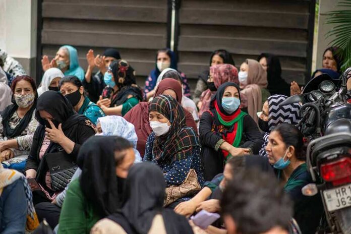 shutterstock_2030300909-1 Chuck Howley among a seated crowd of masked women outdoors