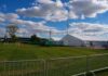 Soccer Chaos: Truck Plows Into Crowd Temporary white tents and equipment on a grassy field with traffic cones and metal barriers