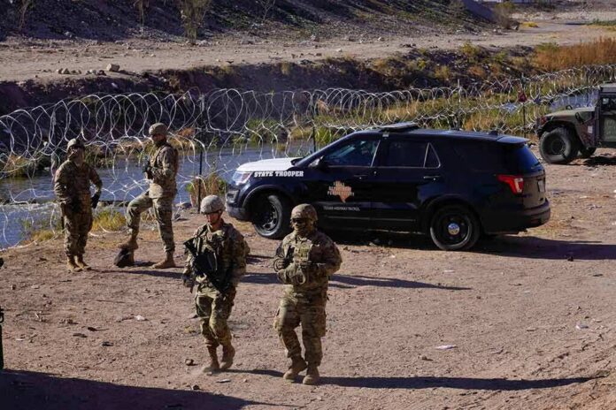shutterstock_2241074351 Soldiers stand near barbed wire beside a police SUV