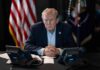 GOP Erupts After Trump Backs Attack Ad Donald Trump seated at a table between two desk phones