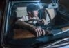 young man in a car holding a rifle