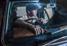 young man in a car holding a rifle