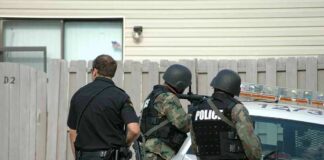 police officers in tactical gear beside patrol car